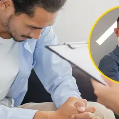 Mężczyzna w niebieskiej koszuli pochyla się nad dokumentami, obok uśmiechnięty urolog. Tak wygląda badanie prostaty u urologa.