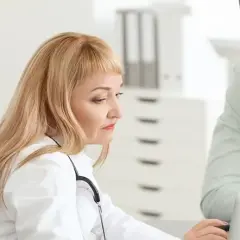 Lekarka z laptopem i stetoskopem rozmawia z pacjentem. Pytanie, kto może przepisać leki na uspokojenie, jest kluczowe dla jego zdrowia.