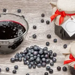 Słoiki z dżemem z jagód, znanych ze swoich właściwości na biegunkę, i miska pełna świeżych owoców.