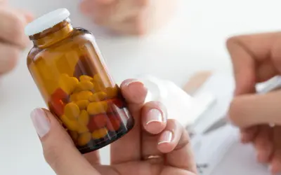 Kobieta trzyma buteleczkę z tabletkami, zastanawiając się nad pominięciem dawki leku Euthyrox. Obok ktoś notuje.