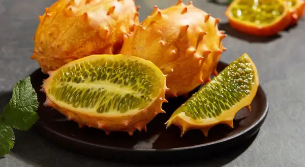 Kiwano, jak jeść? Kolczasty owoc pokrojony na pół, ukazujący zielony, galaretowaty miąższ z pestkami. Idealny do deserów i koktajli.