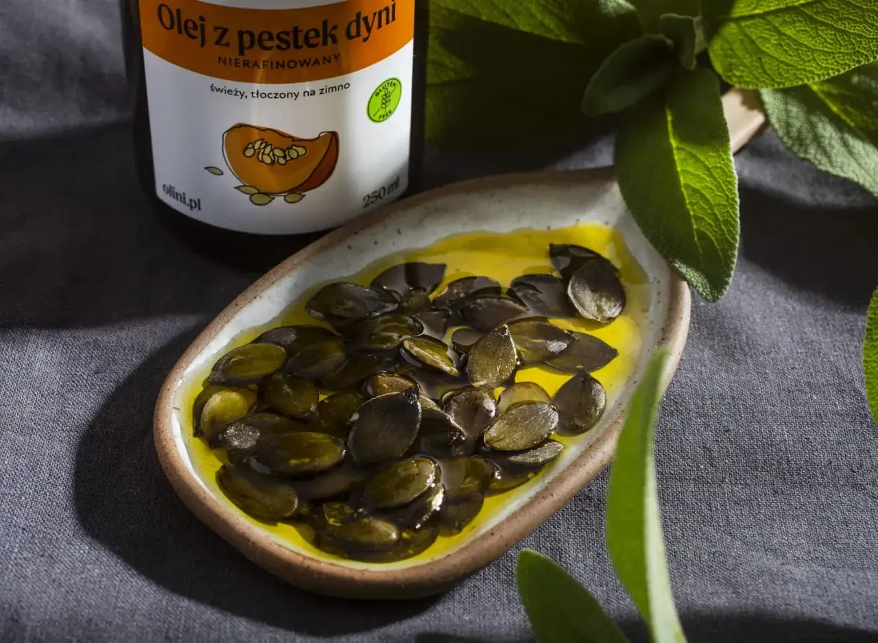 Olej z pestek dyni w miseczce, obok butelki. Warto znać pestki dyni przeciwwskazania, choć są rzadkie.
